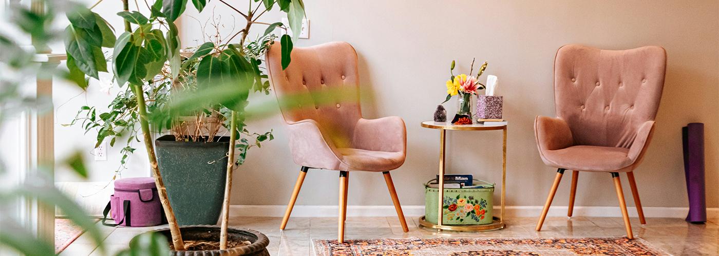 Cozy seating area with pink velvet chairs, plants, and a round table.