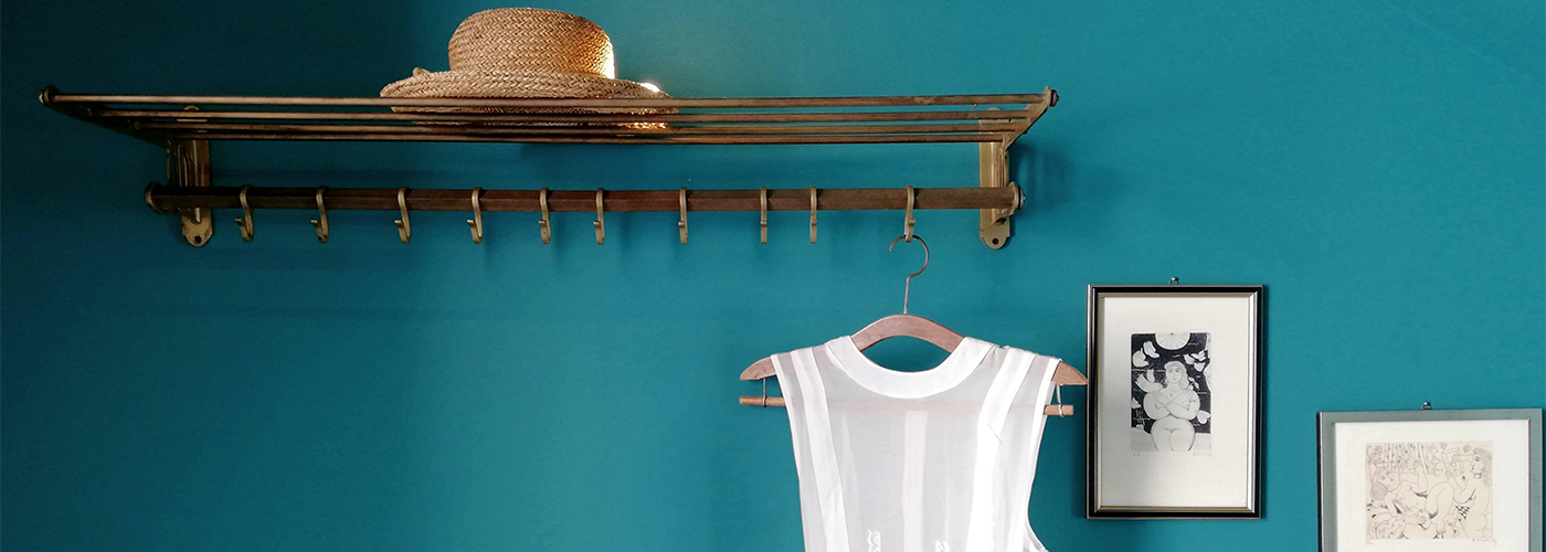 Deep teal painted wall with vintage-style decor and hanging items.