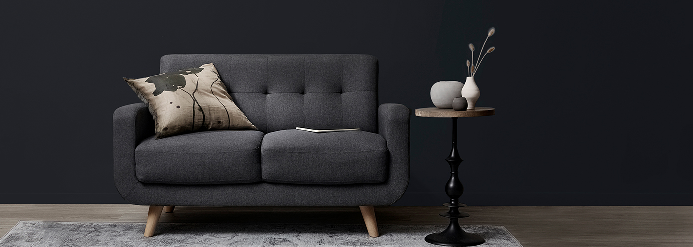 Dark charcoal wall with a modern grey sofa and minimalist decor.
