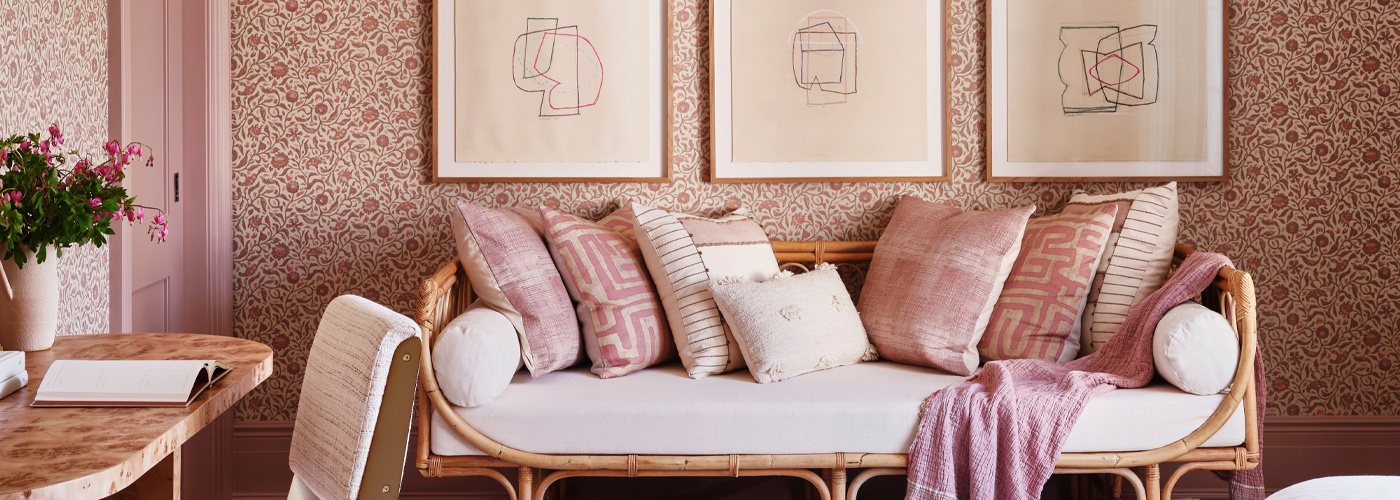 Elegant living space with pink and neutral decor, patterned wallpaper, and framed artwork.